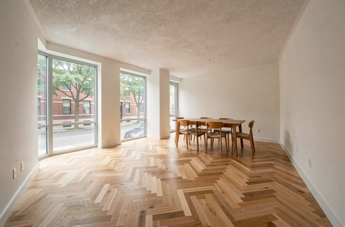 Appartement résidentiel rénové avec parquet en chêne et grandes fenêtres donnant sur une rue urbaine